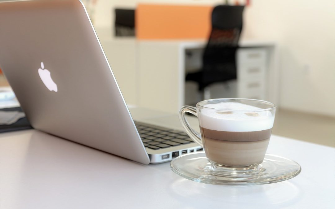 Ordinateur portable ouvert sur une table à côté d’une tasse de café