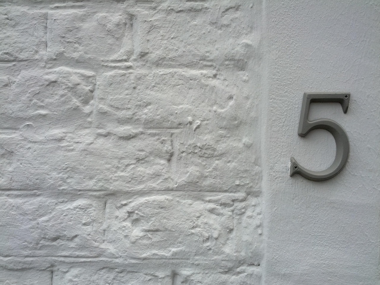 Numéro civique fixé sur un mur de briques blanches