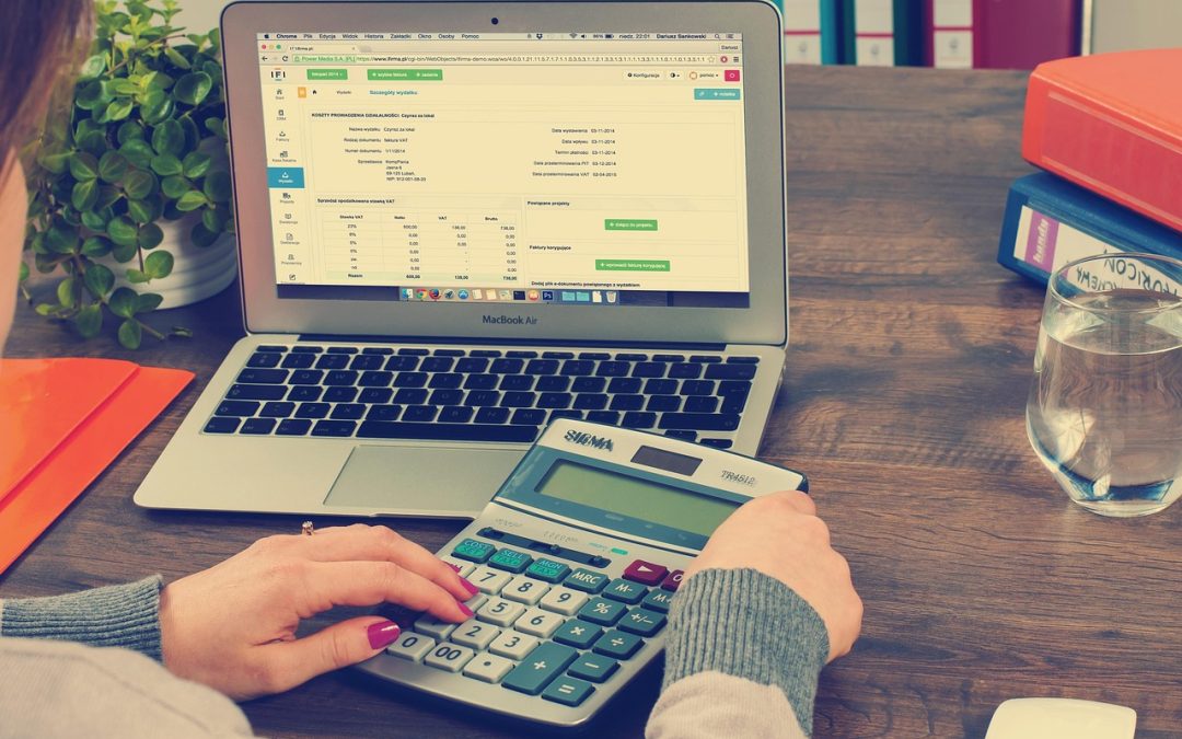 Mains sur une calculatrice à côté de documents comptables