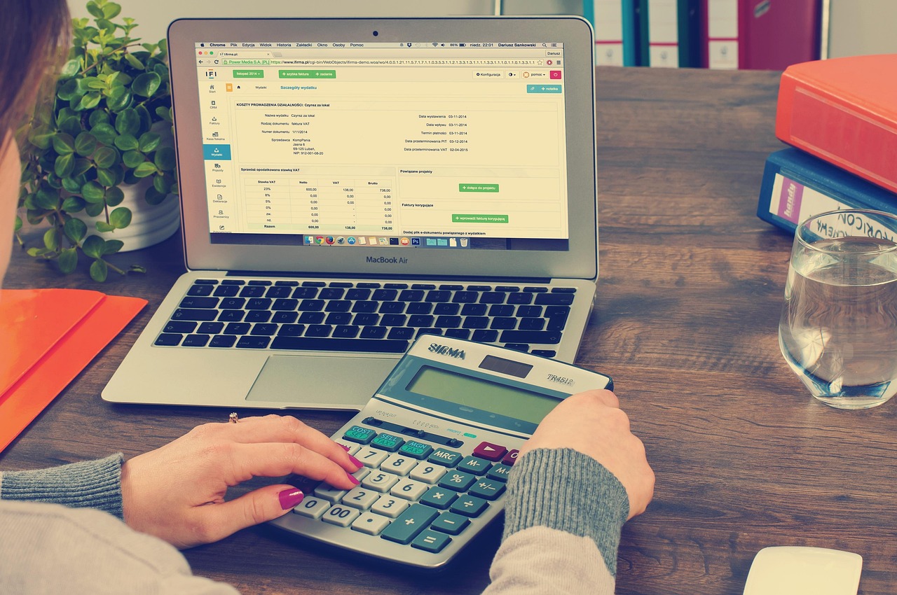 Mains sur une calculatrice à côté de documents comptables